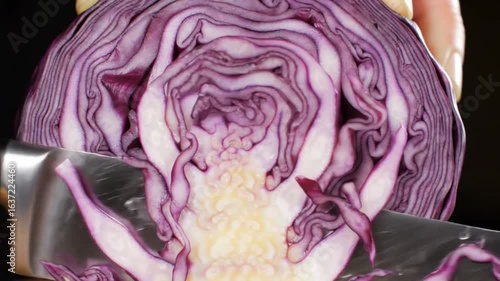 Close up of a knife slicing through a red cabbage head showing the inner layers and core detail