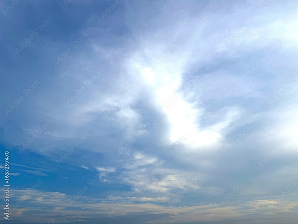 Obraz premium Bright daylight shines through the dynamic white and blue clouds creating atmospheric contrast
