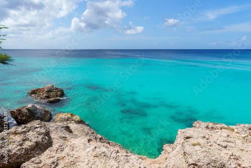 Vista panorâmica do mar azul-turquesa de Curaçao a partir de falésia rochosa, revelando águas cristalinas e beleza natural do Caribe.