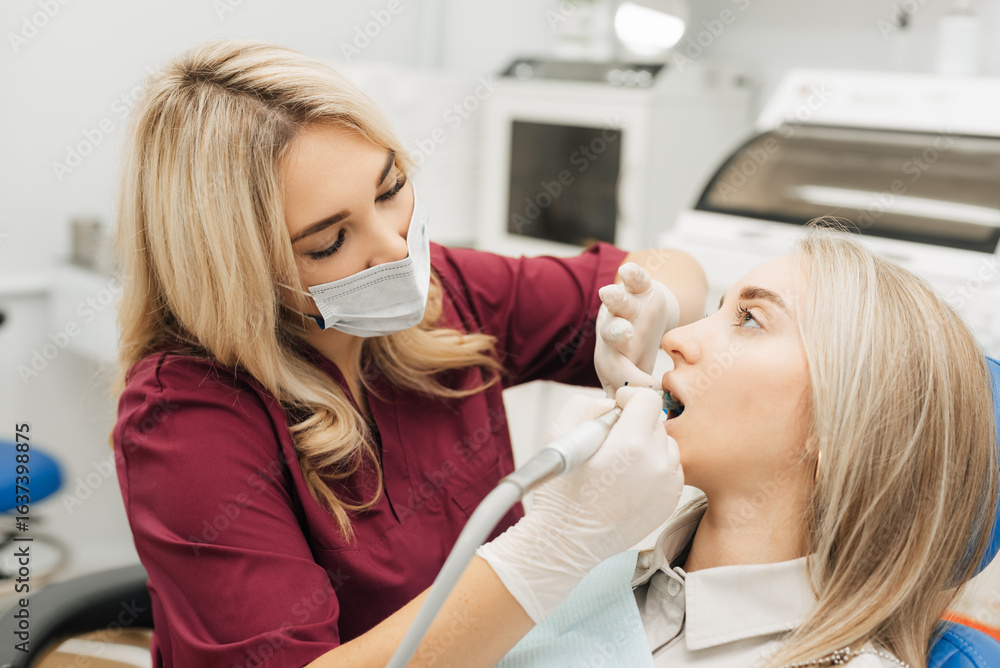 The dentist begins a routine operation to clean the tooth of a woman's mouth. The dentist begins a routine operation to clean the tooth of a woman's mouth.
