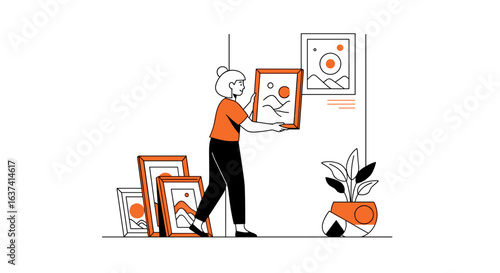 Woman hanging a framed picture on the wall with other pictures and a plant near