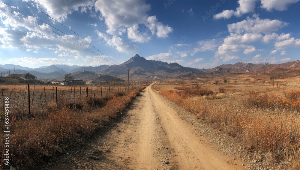 Fototapeta premium Dirt road winds through a dry landscape towards a mountain