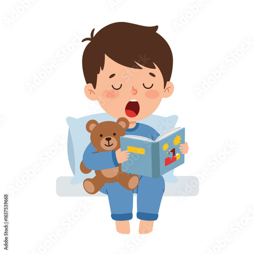 Sleepy young boy in blue pajamas yawning while reading a bedtime story with his teddy bear.