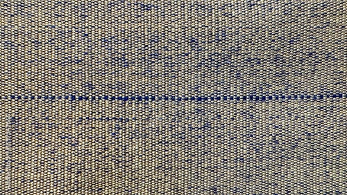 Background of a woven fabric texture in light beige and yellow tones with subtle dark specks and a horizontal thread line in the middle.
