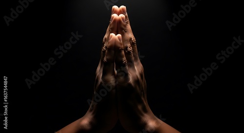 Hands clasped in prayer against a stark black background conveying faith spirituality and seeking guidance representing hope and reflection