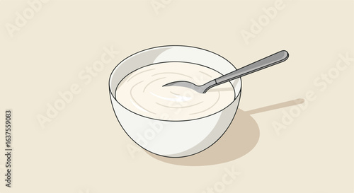 A bowl full of creamy white substance, with a spoon. Light tan backdrop