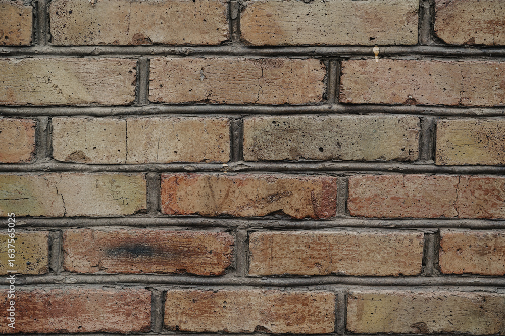 Obraz premium Old weathered brick wall with red and brown bricks