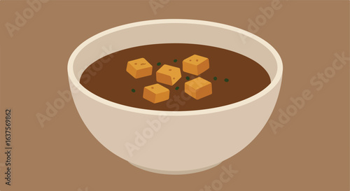 Bowl of soup. Cubes and green flecks float in brown liquid. Neutral background