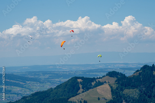 Des personnes qui pratiquent la parapente volent dans le ciel des préalpes suisses