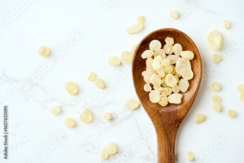 flat lay pile of mastic gum or tear of chios in wood spoon white table food background with copy space