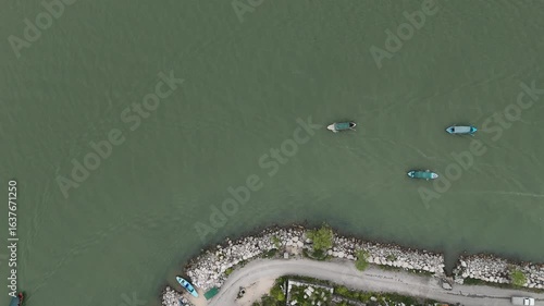Static Top-Down Drone View of Two Traditional Vessels with Wakes, Rocky Shoreline, and a Third Boat 