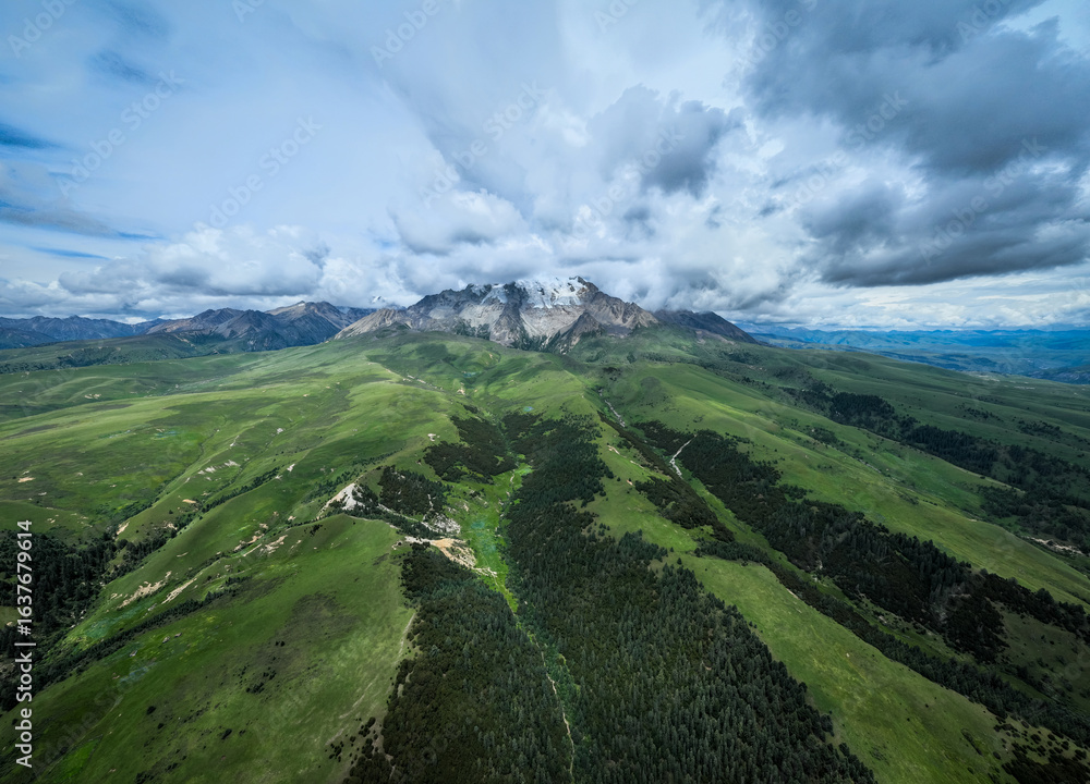 Naklejka premium Aerial view of beautiful high altitude snow capped mountains and forest grassland landscape in China