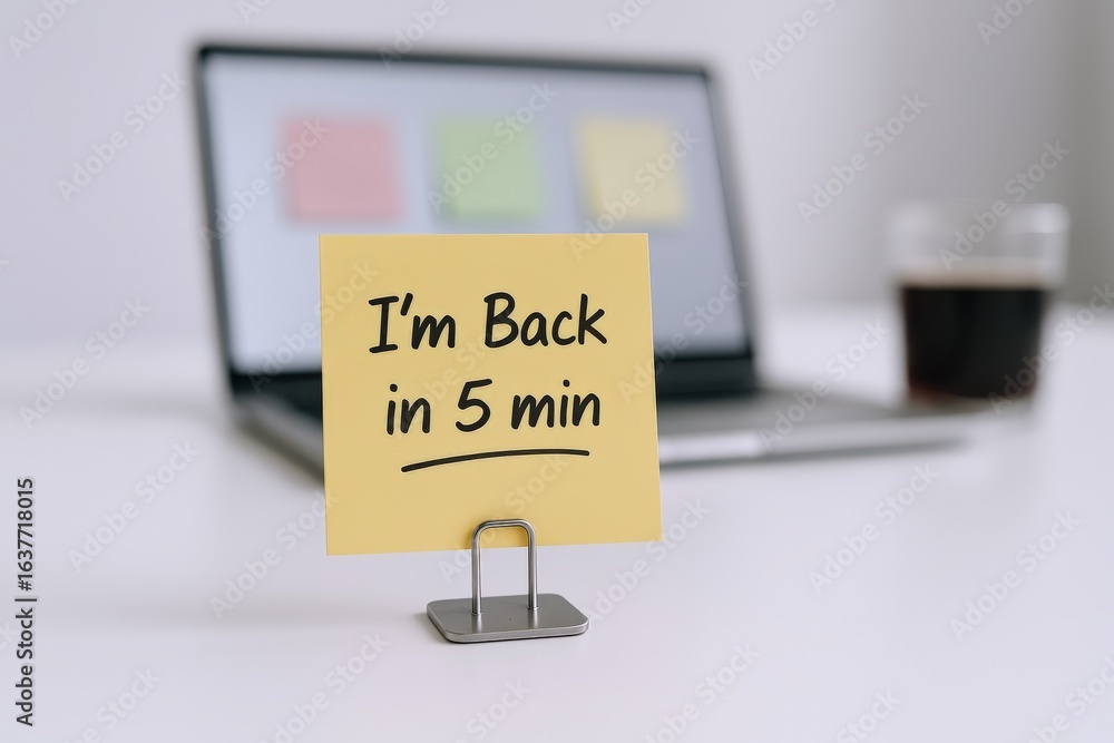 Naklejka premium Office Break Reminder: Note Saying 'Back in 5 Minutes' on Desk with Laptop