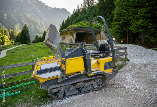 Compact tracked dumper at construction site in alpine mountain landscape
