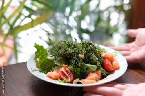 Caulerpa fresh green sea grape on wooden. plate of asian salad delicious in a restaurant beautiful presentation luxury delicacy