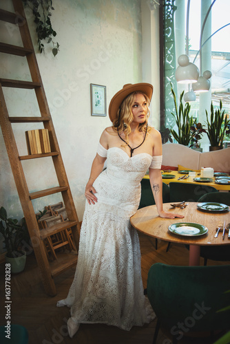  Beautiful slim blonde poses in boho wedding dresses and an embroidered corset on a summer terrace.