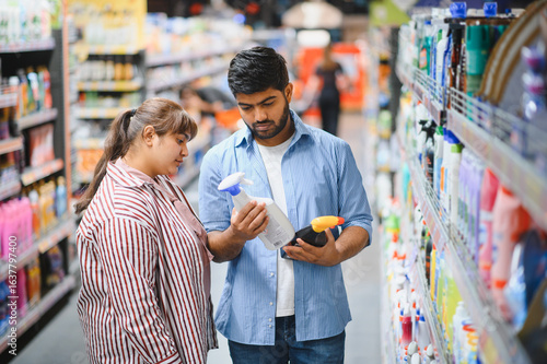 Valokuva Indian couple choosing cleaning products in supermarket household chemicals aisl