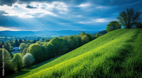 Lush Green Hillside Meadow with Sunlight Bursting Through Clouds, Creating a Scenic and Serene Landscape