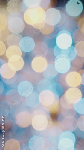 Vertical Screen: Christmas defocused ice skating rink bokeh background. Shimmering abstract warm circles defocused. Blurred fairy lights. Out of focus holiday background.