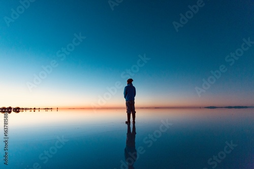 ボリビアの早朝のウユニ塩湖に立つ男性のシルエット