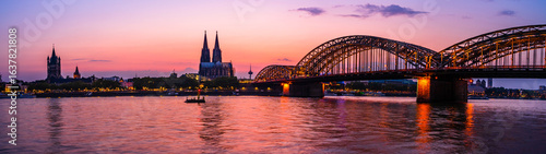 Silhouette skyline landscape of the gothic Cologne Cathedral, Hohenzollern railway and pedestrian bridge, the old town and Great St Martin church in Cologne, Germany after sunset into blue hour