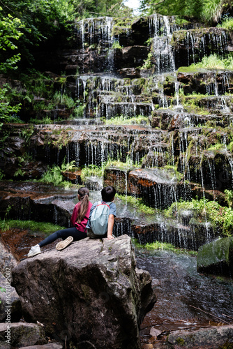 Valokuva Young hikers admiring cascading waterfall in lush forest