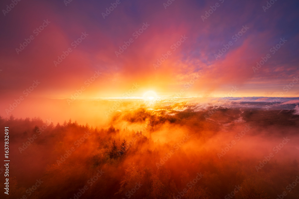 Fototapeta premium An incredible sunset paints the sky with fiery red and orange hues over the Murg Valley in Germany's Northern Black Forest. Thick mist fills the valley, creating a dramatic and powerful scene.