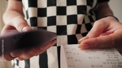 Woman using smartphone to calculate bill after shopping at the supermarket. Close up of hands checking grocery receipt, using a budgeting and money saving mobile apps. High quality 4k footage
