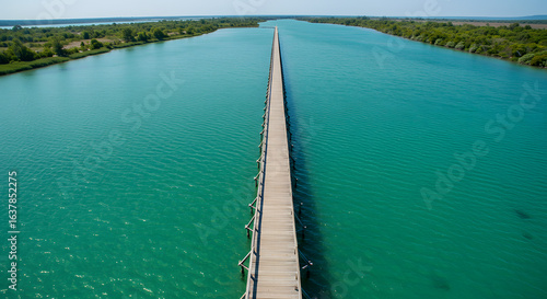 Wallpaper Mural Expansive wooden bridge stretching across tranquil turquoise river with lush green riverbanks Torontodigital.ca