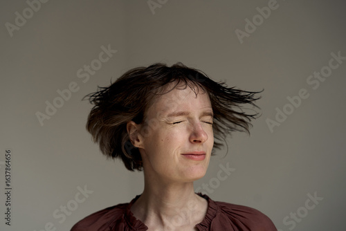 Tableau sur toile Young woman with flowing hair captured in motion against warm lighting in studio