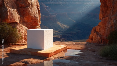 Empty white cube on a ledge overlooking a canyon. Sunlight streams through the rock face