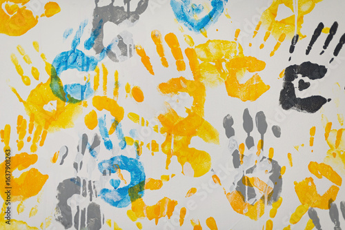 Bright handprints create a colorful mural on a white canvas in a vibrant community art project