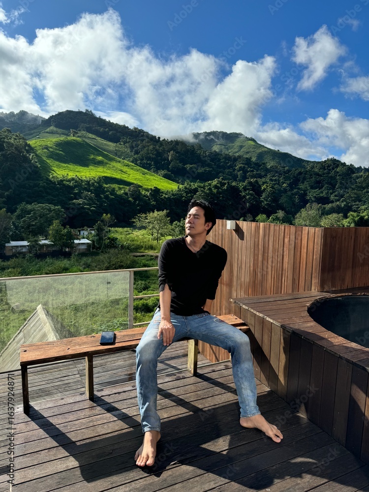 Handsome man relaxing on a holiday at a balcony with a beautiful mountain view.