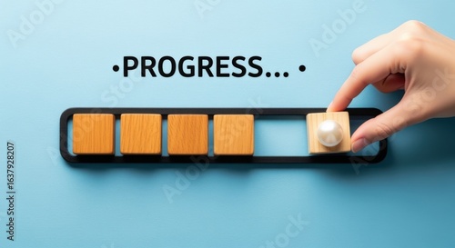 Hand completing progress bar with wooden blocks, showcasing business growth and development on blue background