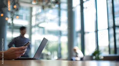 Wallpaper Mural Close-up of person using a smartphone and laptop in a modern office space. Torontodigital.ca