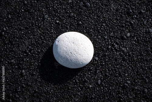 white pebble on black sand, closeup detail, zen vibe