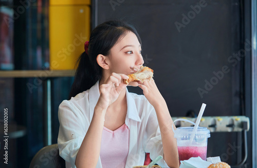 A cute Chinese girl enjoying a hearty meal at a fast-food restaurant in a shopping mall.