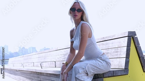 Pretty blonde gen z woman at the pier in New York City during the summer 
