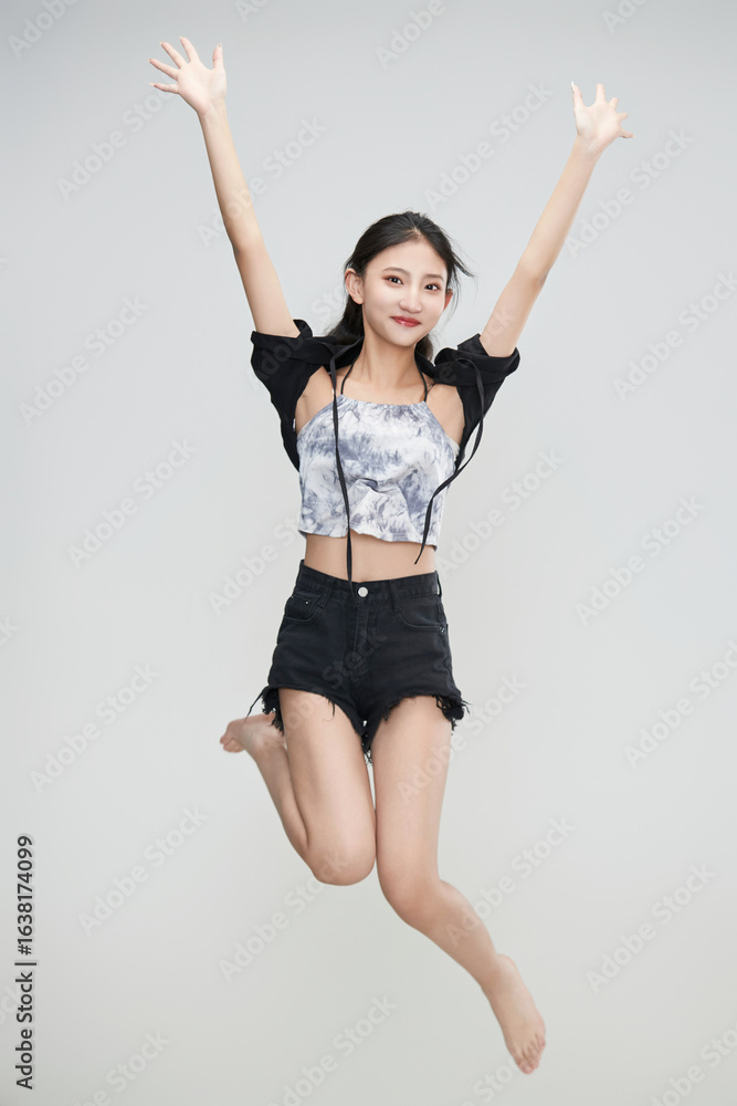 Naklejka premium Cute Asian girl leaping in the air against a white background