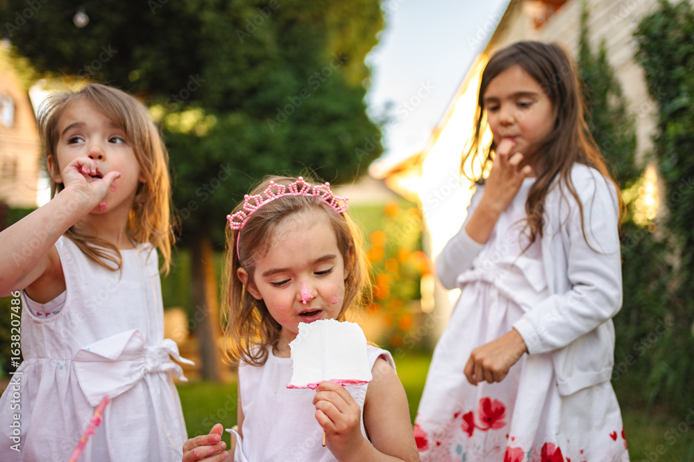 Three cheerful girls savoring treats in a sunny garden Three cheerful girls savoring treats in a sunny garden
