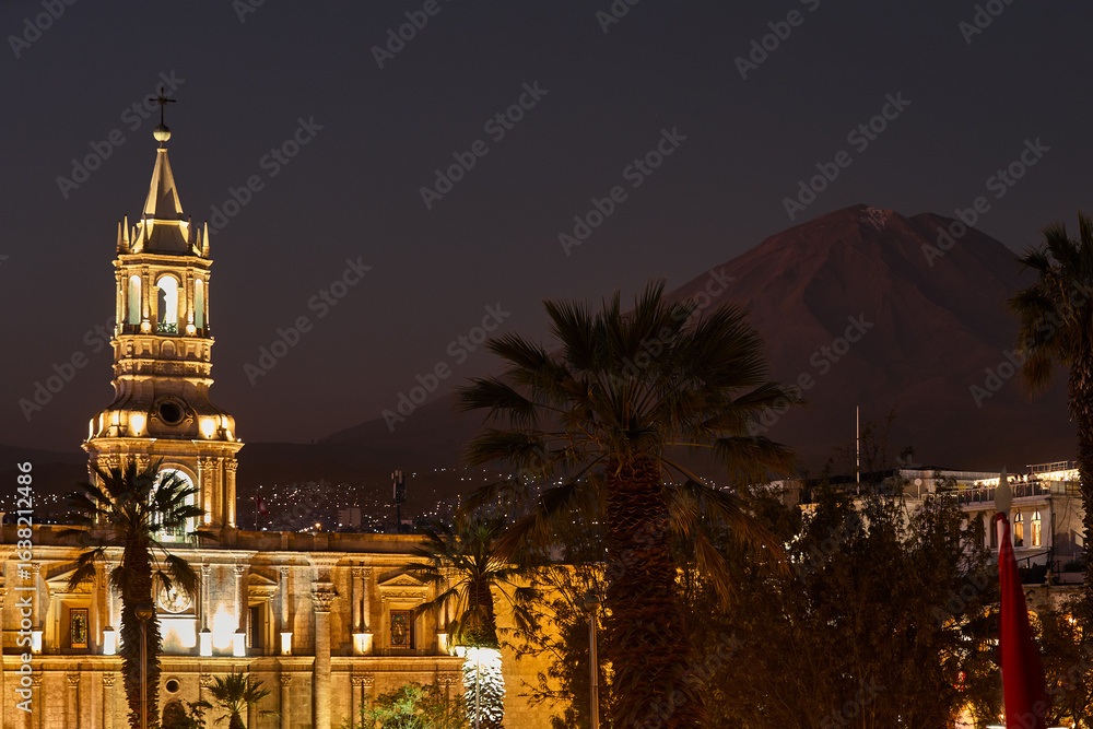 Fototapeta premium The sun sets over the Plaza de Armas in Arequipa, casting golden light on the majestic Basilica Cathedral. Misti Volcano on the background