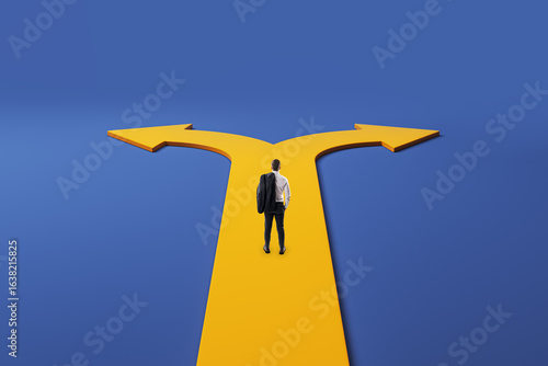 Fotografija Businessman standing at forked yellow path, choosing between two directions against a blue background, symbolizing decision-making dilemma