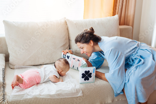 Εκτύπωση καμβά Young mother playing with newborn baby during tummy time at home