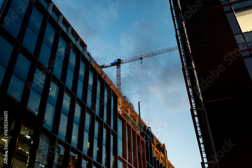 Photography Modern building construction in Dublin with tower crane against evening sky