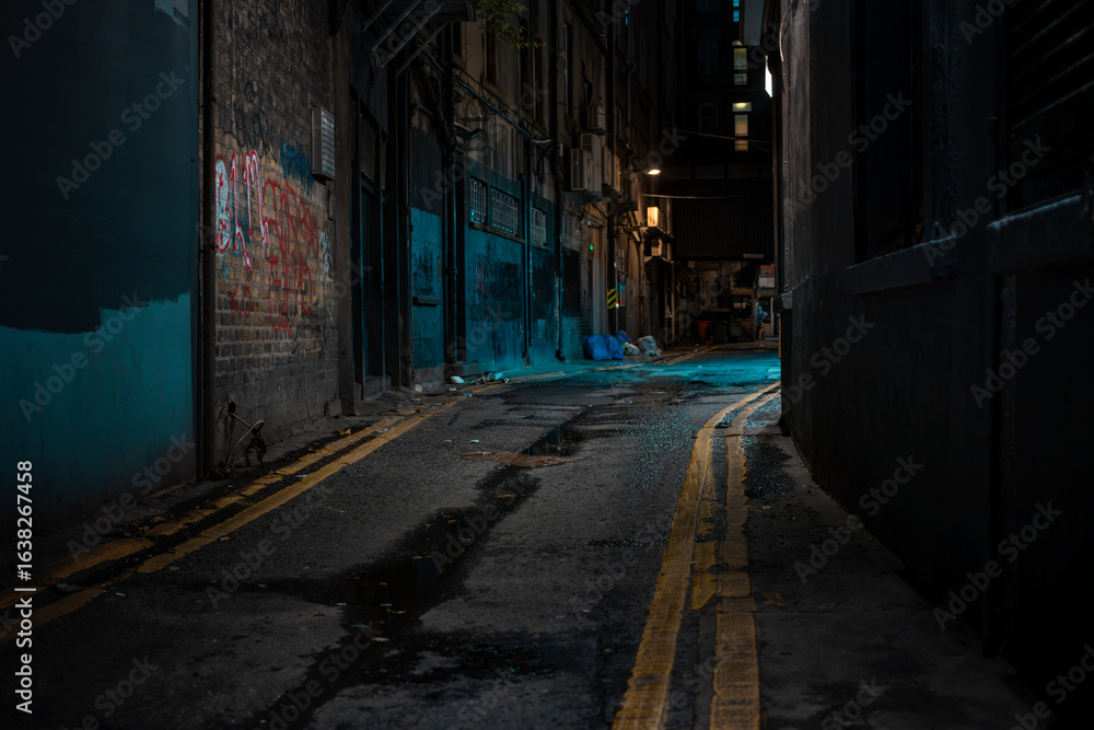 Obraz premium Dark Dublin alley with graffiti street art and atmospheric blue lighting. Urban underground scene with wet pavement and industrial architecture.