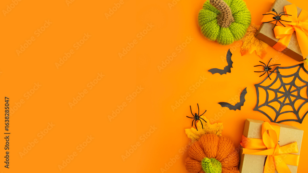 Knitted orange pumpkins and black bats on an orange background, autumn composition, front view.Happy Halloween holiday concept.