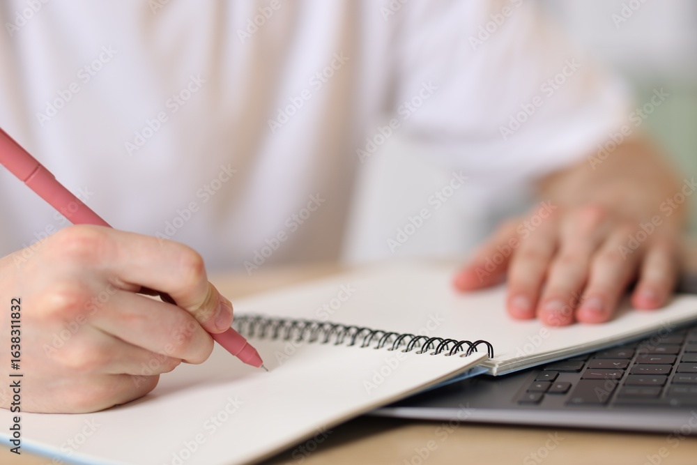 Fototapeta premium Man writing in notepad with pen at table, closeup