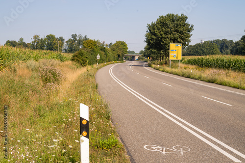 Foto Winding country road with bike lane and corn fields in germany