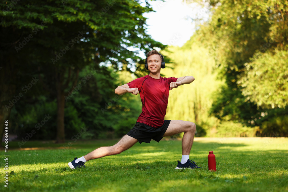 Smiling sportsman in headphones doing morning exercise outdoors Smiling sportsman in headphones doing morning exercise outdoors