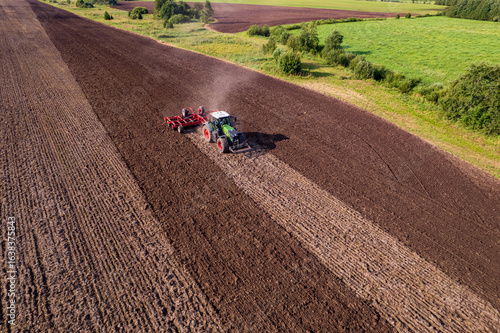 tractor cultivating a field with a harrow